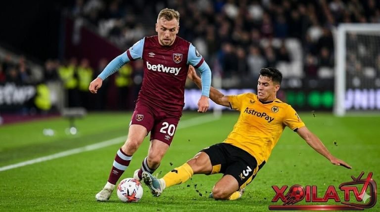 Xoilac TV diem nong tran dau West Ham vs Wolves, hinh anh can canh Jarrod Bowen (West Ham, so 20) dốc bóng va cắt chéo vao khu vực half-space, cơ bắp căng thẳng và mồ hôi rơi, đang đối đầu trực tiếp voi Santiago Bueno (Wolves, so 3) đang xoạc bóng va truy cản quyết liệt. Cả hai cầu thủ thể hiện sự quyết tâm tột độ, biểu cảm gương mặt căng thẳng